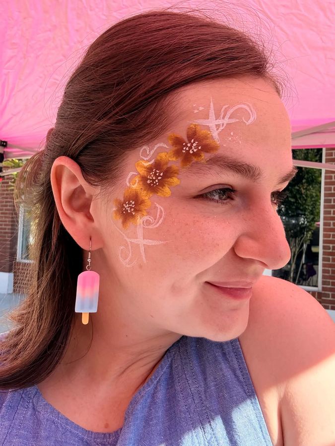 Golden flower and white swirl cross design on the temple, In His Image face painting, serving Dandridge TN
