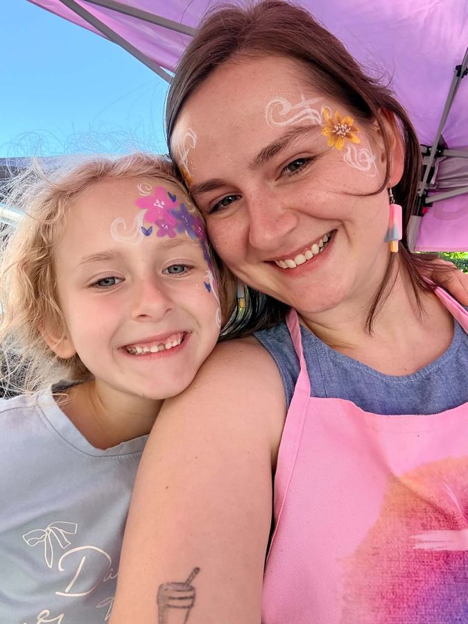 Ashley and a smiling girl both wearing flower and butterfly face paint, In His Image face painting, serving Morristown TN